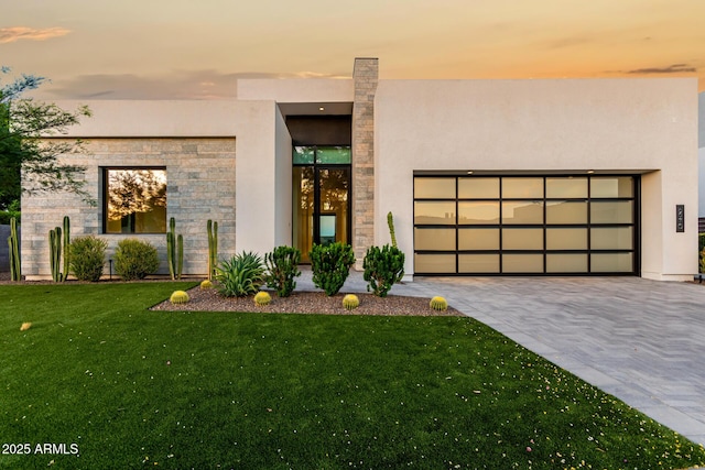 6970 E Joshua Tree Ln, Paradise Valley, AZ 85253 - modern home with stucco siding, a front yard, an attached garage, stone siding, and decorative driveway