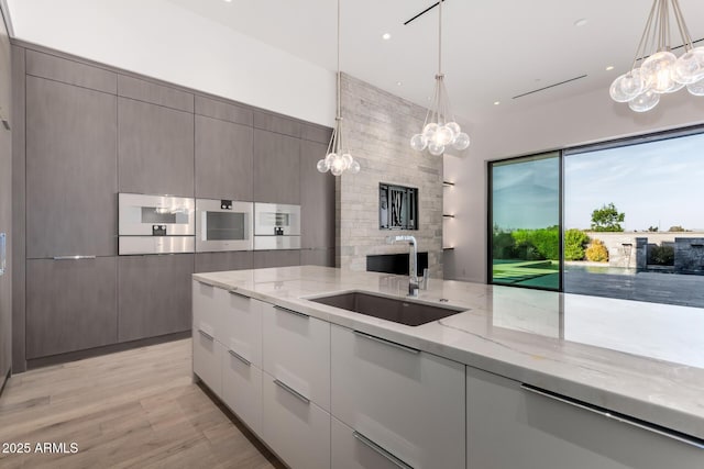 6970 E Joshua Tree Ln, Paradise Valley, AZ 85253 - kitchen featuring a sink, a chandelier, modern cabinets, light stone counters, and recessed lighting
