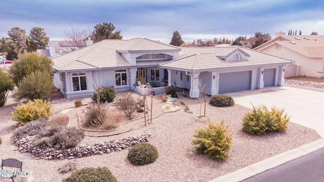 view of front of home featuring an attached garage, a tile roof, concrete driveway, and stucco siding