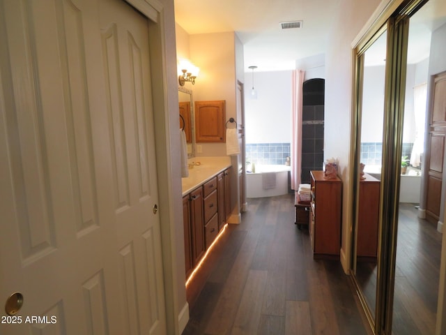 hall featuring dark wood-type flooring and visible vents