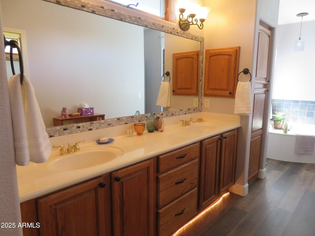 full bathroom featuring plenty of natural light, a freestanding tub, a sink, and wood finished floors