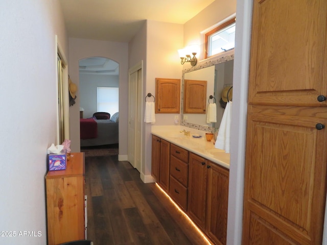 full bath with double vanity, baseboards, connected bathroom, wood finished floors, and a sink