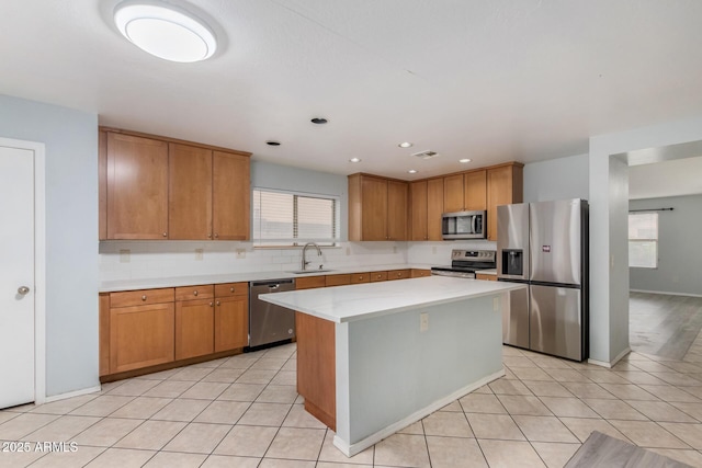 kitchen with a healthy amount of sunlight, a center island, light tile patterned flooring, and stainless steel appliances