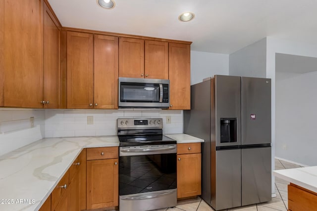 kitchen featuring light stone counters, light tile patterned floors, stainless steel appliances, and tasteful backsplash