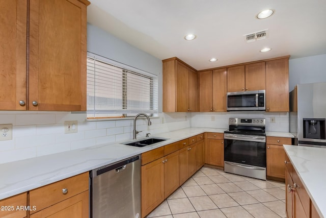 kitchen featuring sink, decorative backsplash, light tile patterned floors, appliances with stainless steel finishes, and light stone counters