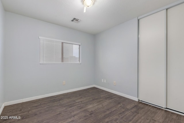 unfurnished bedroom featuring dark hardwood / wood-style flooring and a closet