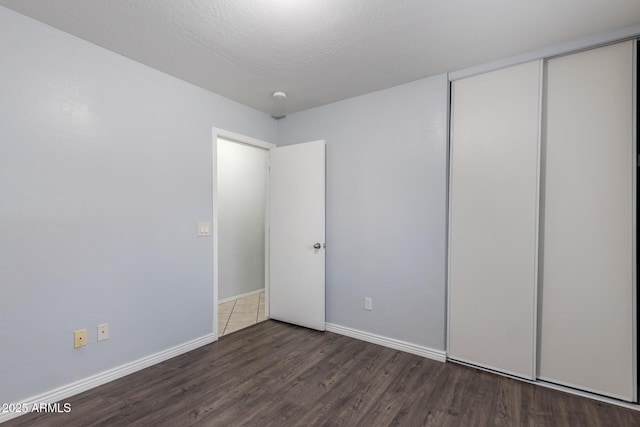 unfurnished bedroom with dark hardwood / wood-style flooring, a textured ceiling, and a closet