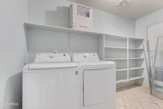 clothes washing area with washer and clothes dryer and light tile patterned floors