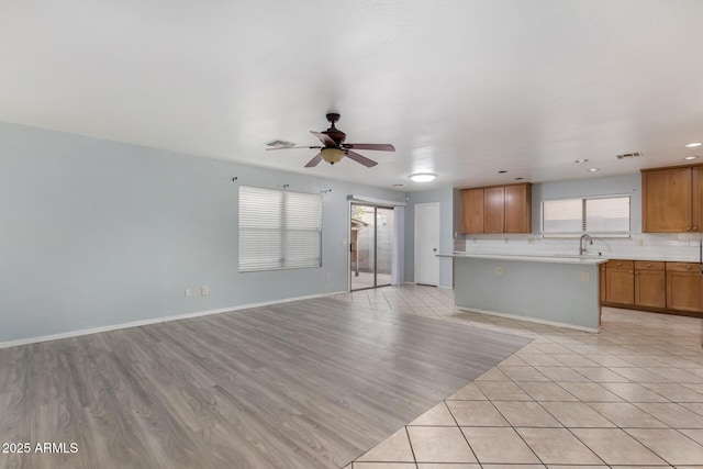 unfurnished living room with ceiling fan, light tile patterned flooring, and sink