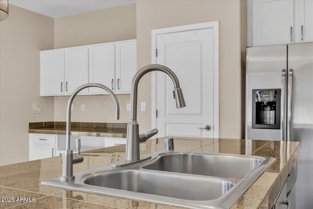 details with stainless steel fridge with ice dispenser, sink, and white cabinets