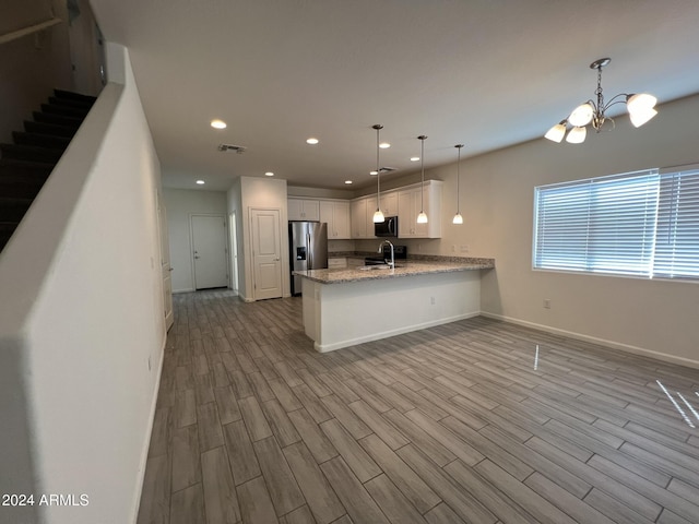 kitchen with sink, kitchen peninsula, light hardwood / wood-style floors, white cabinets, and appliances with stainless steel finishes