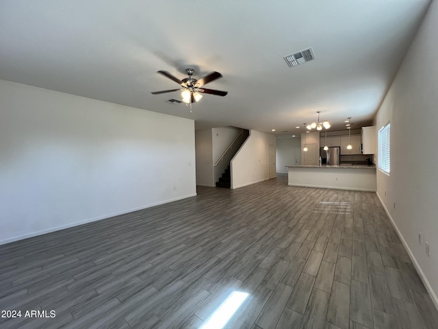 unfurnished living room with dark hardwood / wood-style floors and ceiling fan with notable chandelier