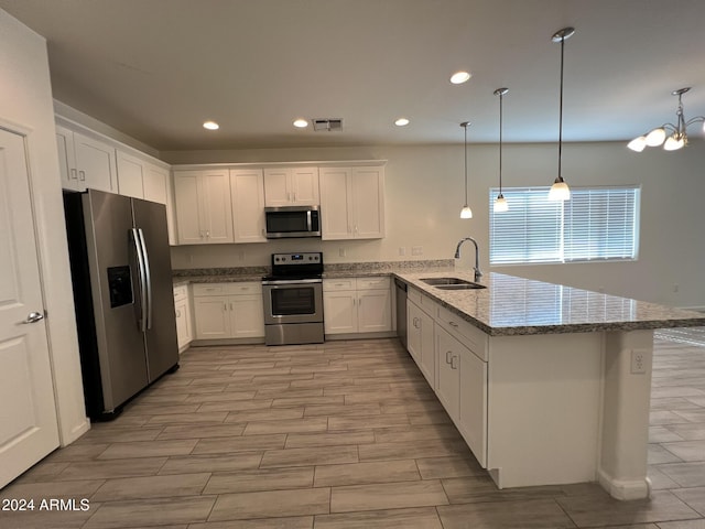 kitchen featuring sink, stainless steel appliances, kitchen peninsula, pendant lighting, and white cabinets