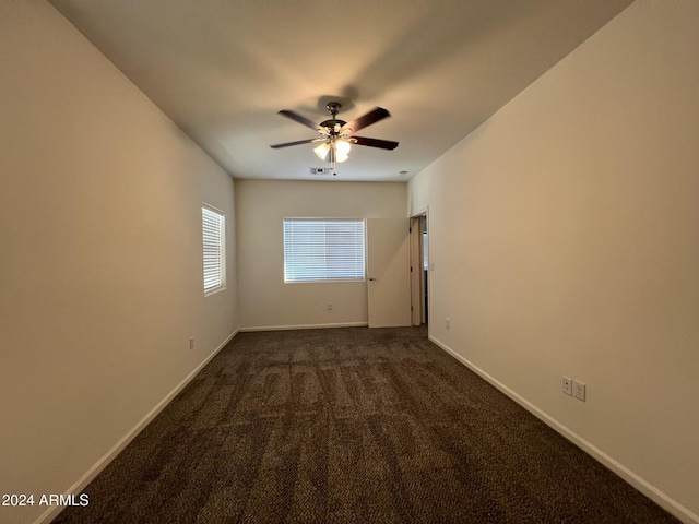 spare room with ceiling fan and dark carpet