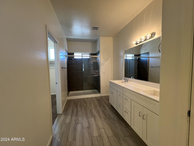 bathroom with hardwood / wood-style floors, vanity, and a shower with shower door