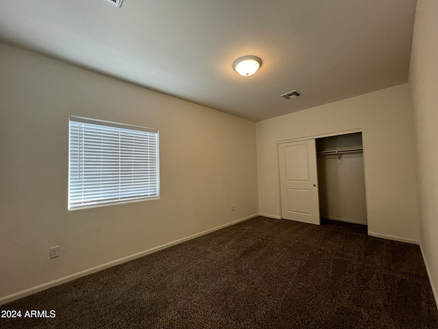 unfurnished bedroom with a closet and dark colored carpet