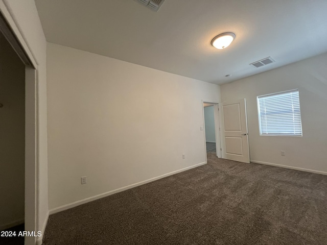 unfurnished bedroom with dark carpet and a closet