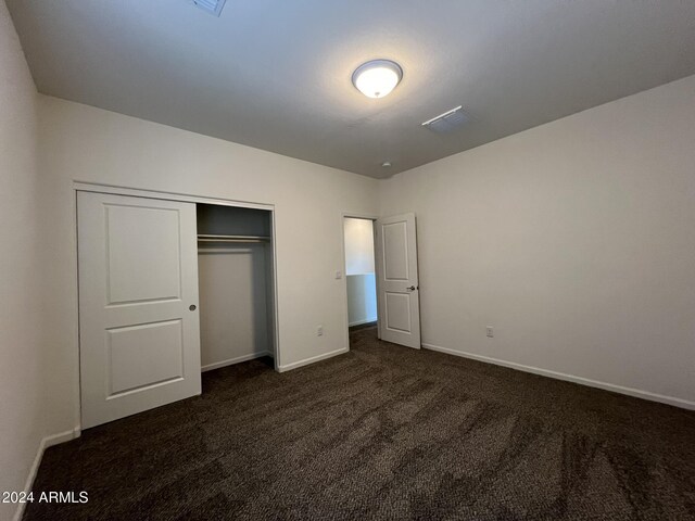 unfurnished bedroom featuring a closet and dark carpet