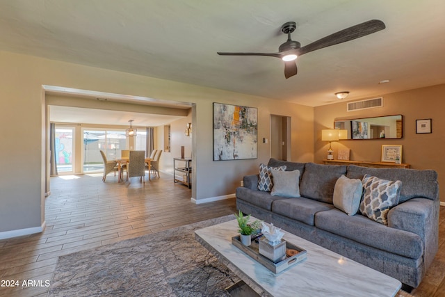 living room with a ceiling fan, wood tiled floor, visible vents, and baseboards