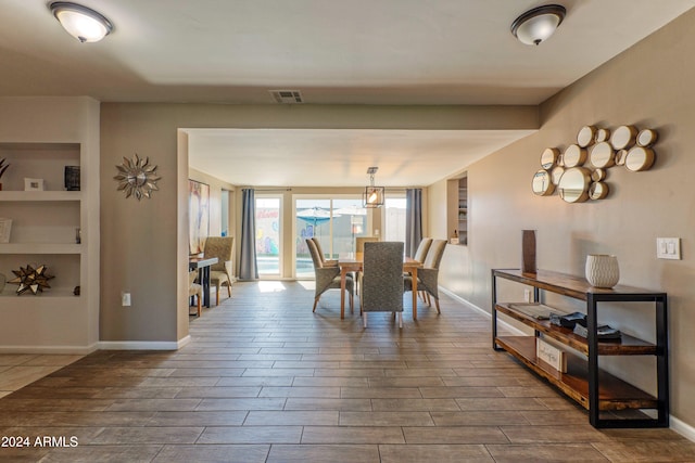 dining space featuring wood tiled floor, visible vents, and baseboards