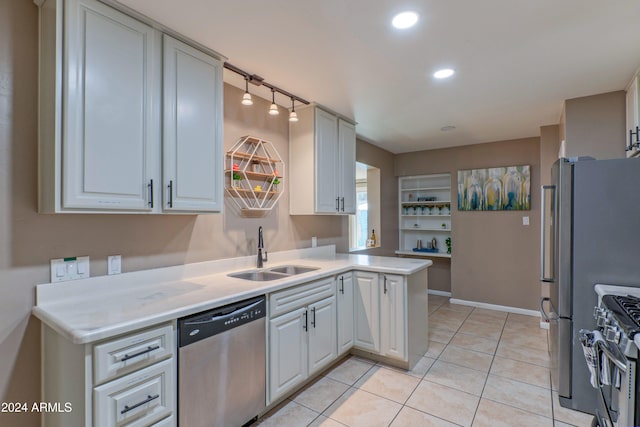 kitchen featuring light tile patterned floors, a peninsula, a sink, light countertops, and appliances with stainless steel finishes