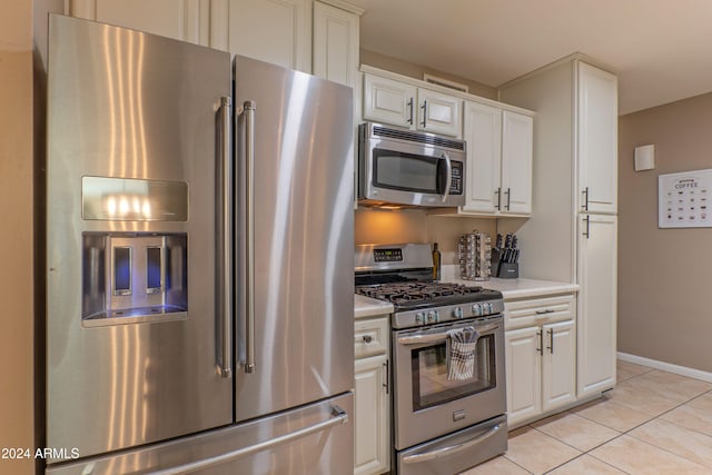 kitchen featuring light tile patterned floors, white cabinetry, baseboards, light countertops, and appliances with stainless steel finishes