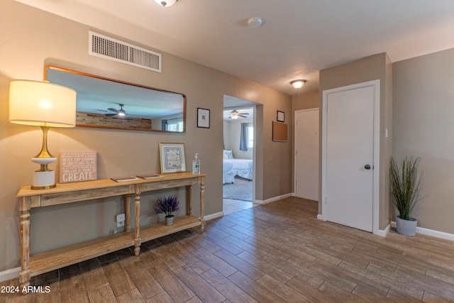hall with baseboards, visible vents, and wood finished floors