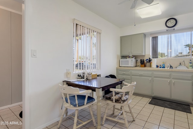 kitchen with tile countertops, white microwave, light tile patterned floors, and a wealth of natural light