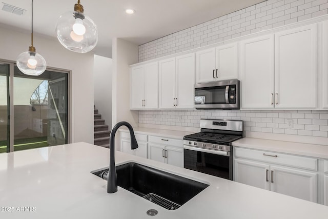 kitchen with stainless steel appliances, light countertops, visible vents, white cabinetry, and a sink