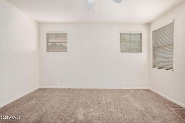 carpeted spare room featuring ceiling fan and baseboards