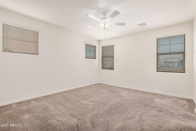 carpeted spare room featuring ceiling fan, visible vents, and baseboards