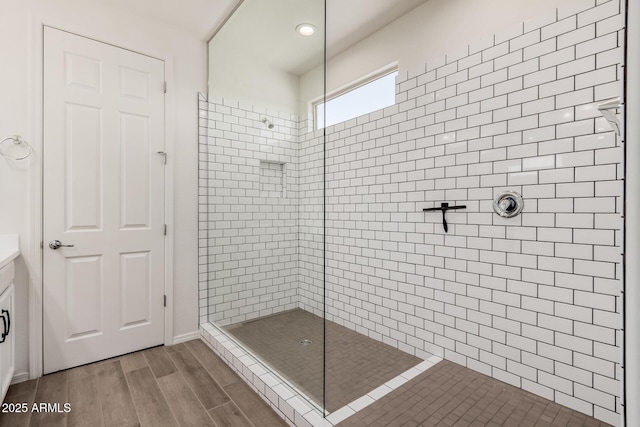 full bath featuring a tile shower and wood finished floors