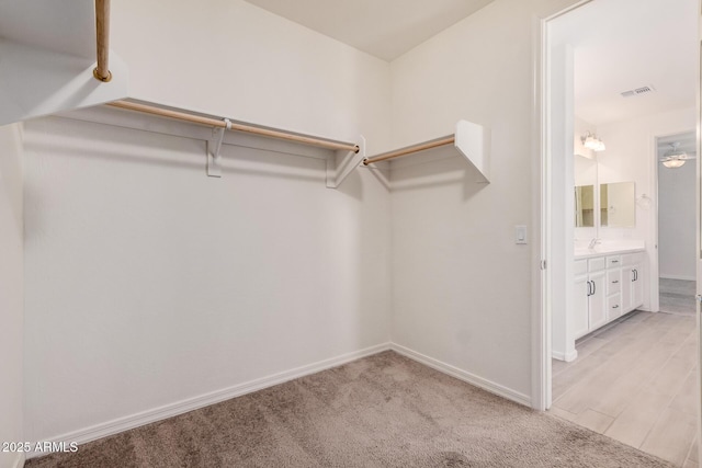 walk in closet with visible vents and light colored carpet