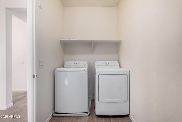 laundry area with laundry area, wood finished floors, washing machine and dryer, and baseboards