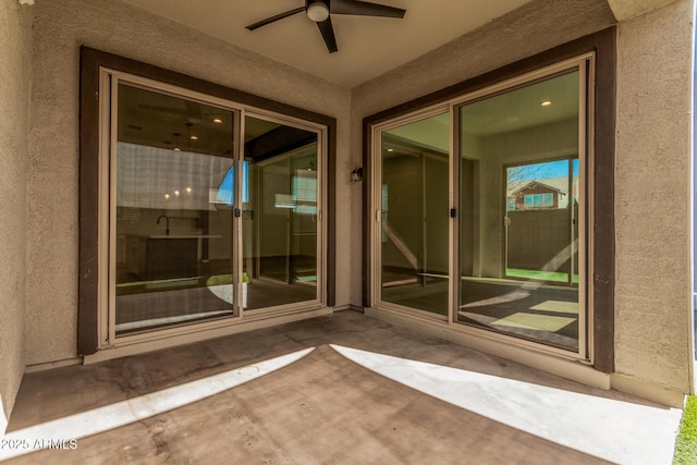 doorway to property featuring ceiling fan, a patio, and stucco siding