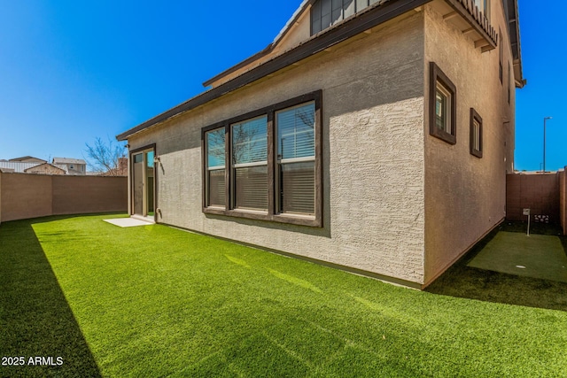 view of property exterior featuring a lawn, a fenced backyard, and stucco siding