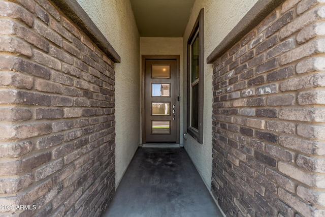 property entrance featuring brick siding and stucco siding