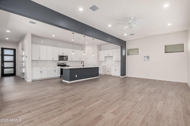 kitchen featuring visible vents, stainless steel appliances, a sink, and open floor plan