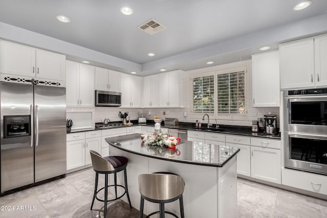 kitchen featuring a kitchen bar, appliances with stainless steel finishes, white cabinetry, and sink