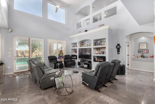 living room featuring ceiling fan, built in features, and a high ceiling