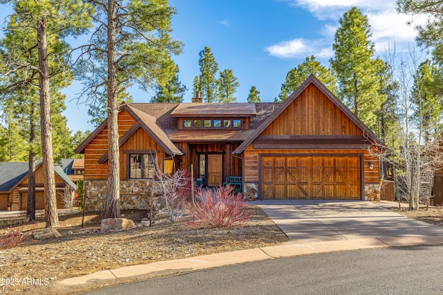 view of front of house featuring driveway, stone siding, a garage, and a chimney