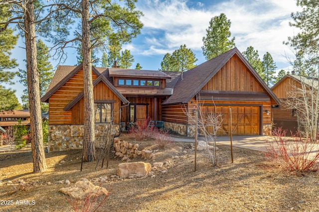 view of front of home featuring stone siding, roof with shingles, driveway, and a chimney