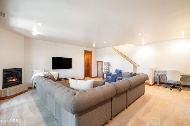 living room featuring recessed lighting, light colored carpet, a glass covered fireplace, and baseboards