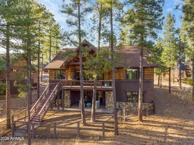 exterior space with a patio area, a fenced front yard, stairs, and stone siding