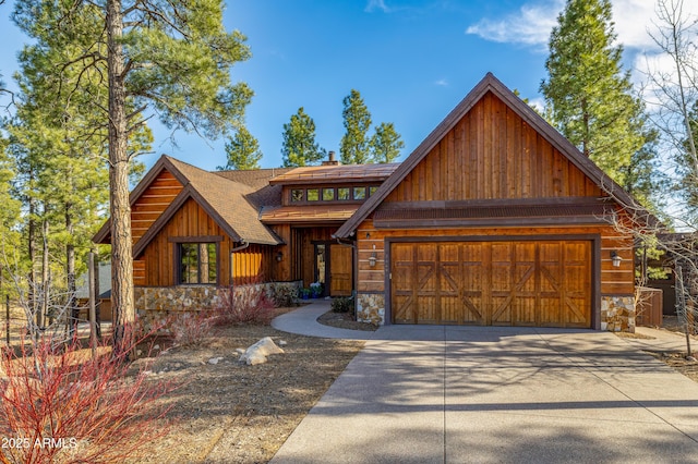 view of front facade with driveway, stone siding, an attached garage, and roof with shingles