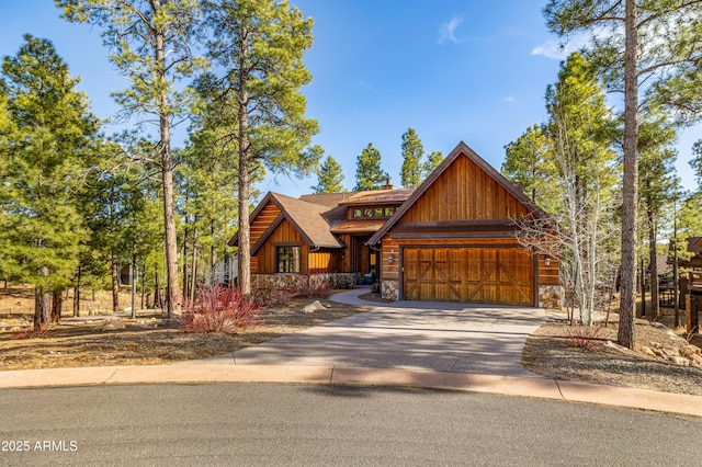 rustic home featuring an attached garage, stone siding, board and batten siding, and concrete driveway