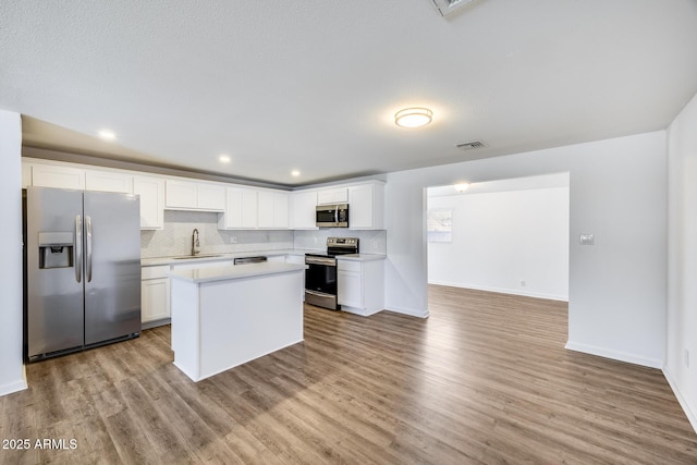 3801 E Captain Dreyfus Ave, Phoenix, AZ 85032 - kitchen featuring stainless steel appliances, light countertops, wood finished floors, a kitchen island, and white cabinetry