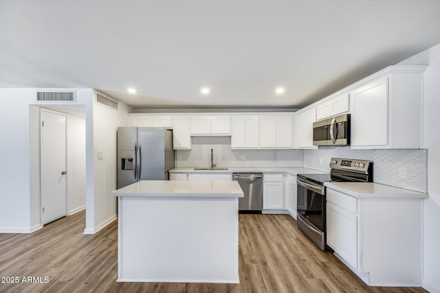 3801 E Captain Dreyfus Ave, Phoenix, AZ 85032 - kitchen with appliances with stainless steel finishes, a center island, light wood-style flooring, tasteful backsplash, and white cabinetry