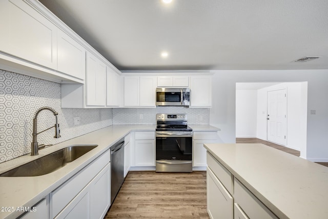 3801 E Captain Dreyfus Ave, Phoenix, AZ 85032 - kitchen with appliances with stainless steel finishes, white cabinets, backsplash, and light wood-type flooring