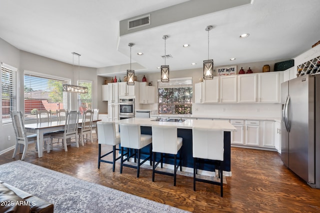 kitchen featuring a center island, light countertops, visible vents, appliances with stainless steel finishes, and white cabinets